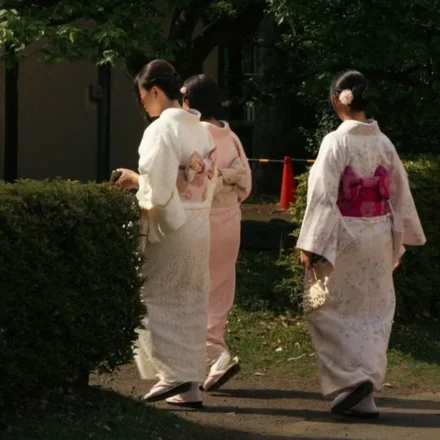 Japanese women wearing traditional kimonos walk through a peaceful park, reflecting cultural heritage.