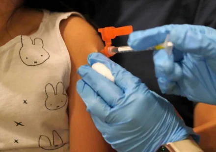 Healthcare worker prepares to vaccinate a child, highlighting updated immunization and public health efforts.