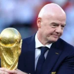 Gianni Infantino holds the FIFA World Cup trophy during a football ceremony. Before the crowd nearby