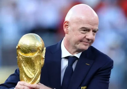 Gianni Infantino holds the FIFA World Cup trophy during a football ceremony. Before the crowd nearby