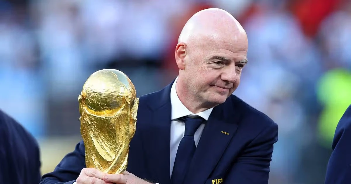 Gianni Infantino holds the FIFA World Cup trophy during a football ceremony. Before the crowd nearby