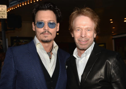 Johnny Depp and Jerry Bruckheimer pose together at a premiere, highlighting their Pirates film link.