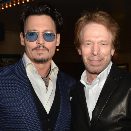 Johnny Depp and Jerry Bruckheimer pose together at a premiere, highlighting their Pirates film link.