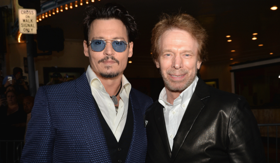 Johnny Depp and Jerry Bruckheimer pose together at a premiere, highlighting their Pirates film link.