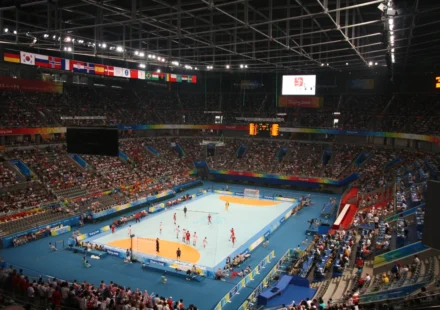Crowded National Indoor Stadium hosts a handball match with athletes competing before a large crowd.