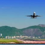 Passenger plane approaches a runway with Rio de Janeiro's mountains and waterfront clearly in view.