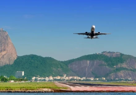 Passenger plane approaches a runway with Rio de Janeiro's mountains and waterfront clearly in view.