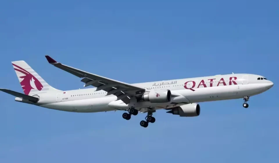 Qatar Airways passenger aircraft approaching for landing under a clear blue sky with landing gear deployed safely.
