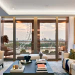 Modern living room with layered lighting, floor to ceiling windows and natural daylight inside.