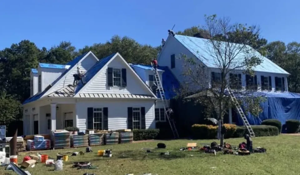 Cotality Housing Report Signals Regional Rebalancing Workers repair a suburban home's roof as construction materials and ladders surround this property.