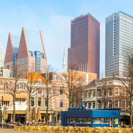 Modern commercial district with historic buildings, cafes, and tall towers beneath a clear blue sky.
