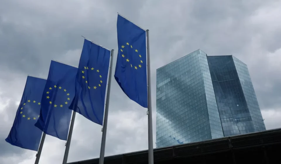 European Union flags fly outside the European Central Bank headquarters beneath dark clouds in Frankfurt, Germany.