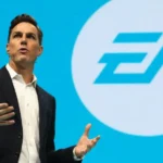 EA executive speaks on stage with the Electronic Arts logo displayed on a large screen behind him.