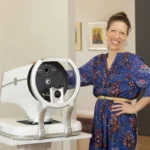 Woman standing beside advanced eye examination equipment in a clinic setting for glaucoma treatment.
