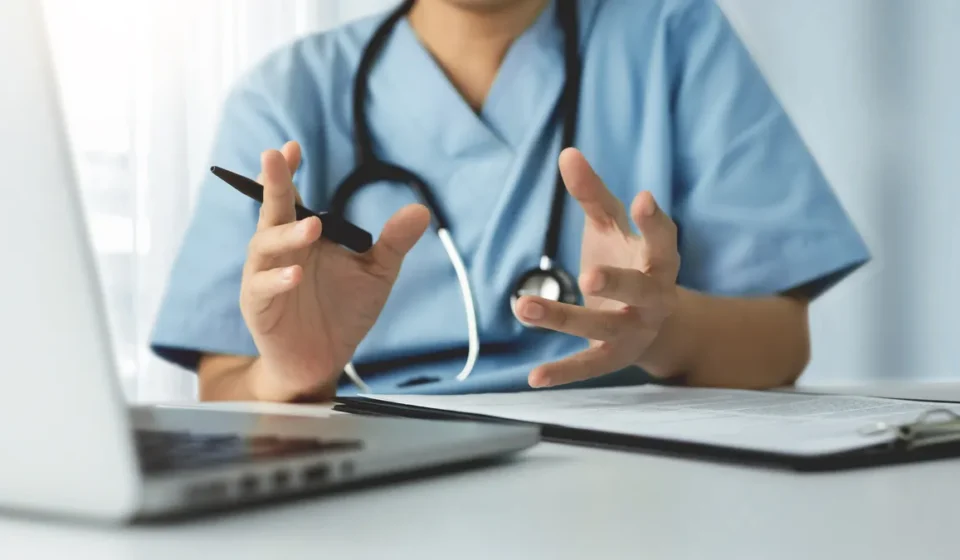 FTC Sues Telehealth Provider Over Patient Data Sharing Doctor conducts a telehealth consultation while discussing patient care using a laptop and clipboard.