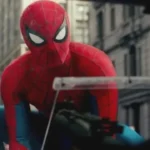 Spider Man in his red and blue suit crouches on a city street during a tense action scene nearby now