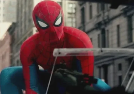 Spider Man in his red and blue suit crouches on a city street during a tense action scene nearby now