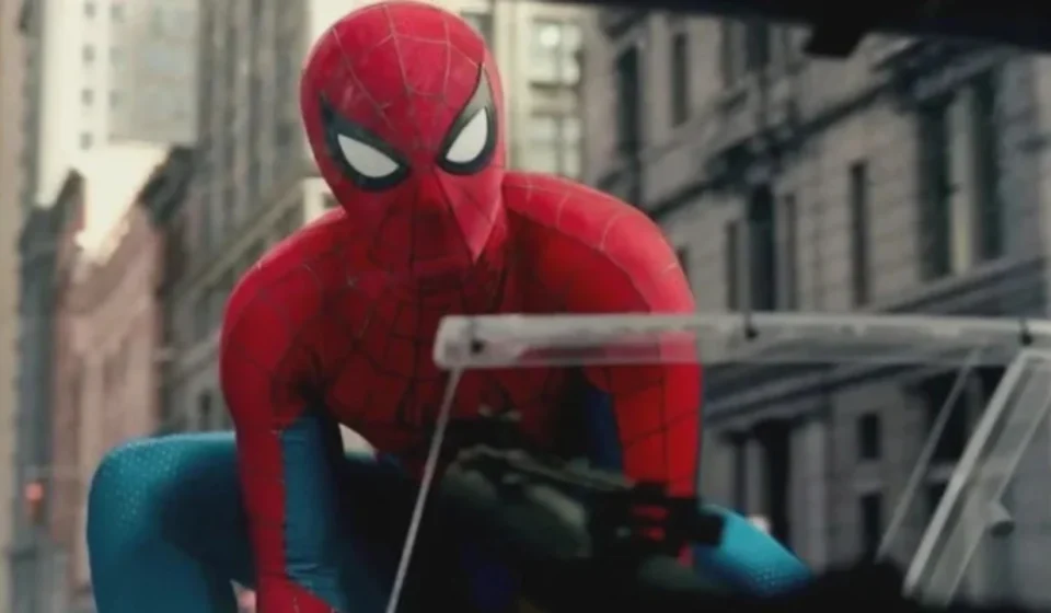 Spider Man in his red and blue suit crouches on a city street during a tense action scene nearby now