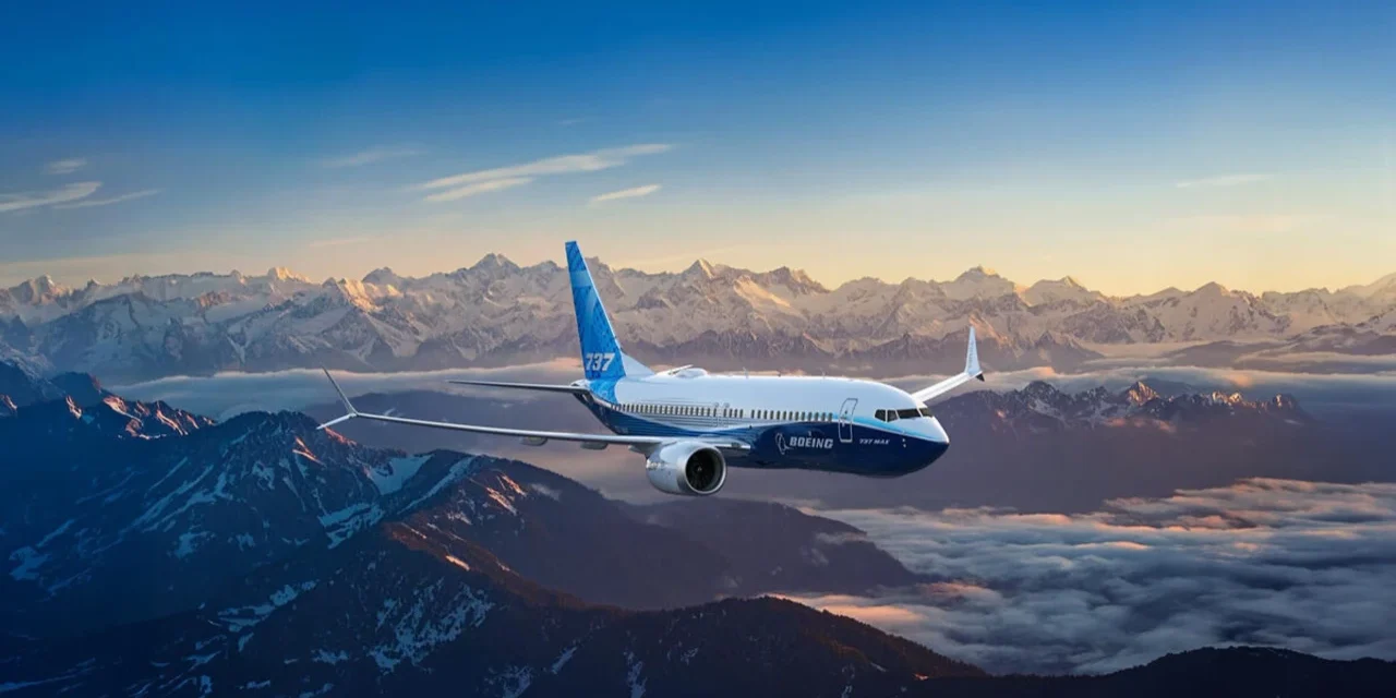 Boeing passenger jet flying above snow covered mountain peaks during sunrise with clear skies and clouds below