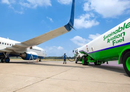 Airliner being refueled with sustainable aviation fuel from a green tanker at an airport apron today