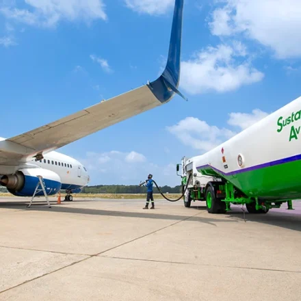 Airliner being refueled with sustainable aviation fuel from a green tanker at an airport apron today