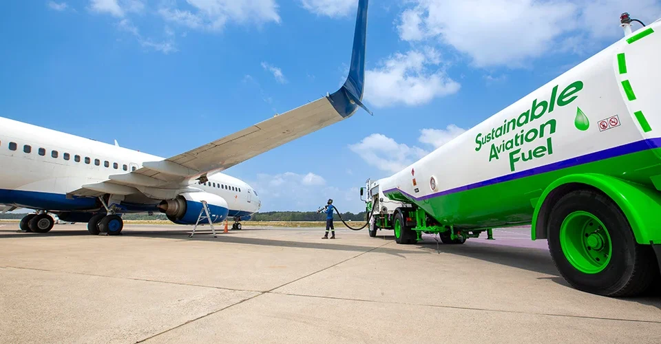 Airliner being refueled with sustainable aviation fuel from a green tanker at an airport apron today