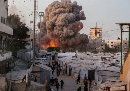 Smoke rises over tents in Gaza as explosion erupts near people seeking shelter nearby amid conflict.