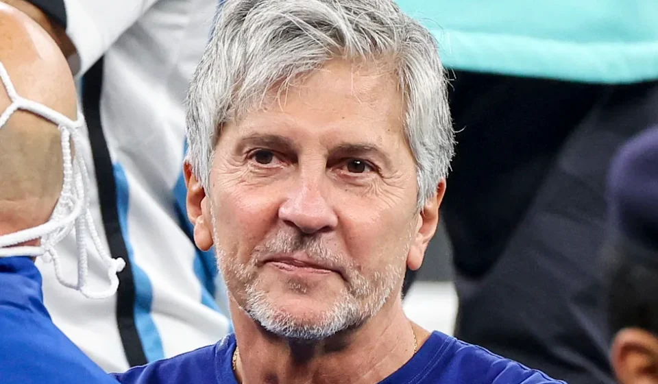 Jorge Messi watches from the stands at a football match, wearing a blue shirt, gray hair and beard.