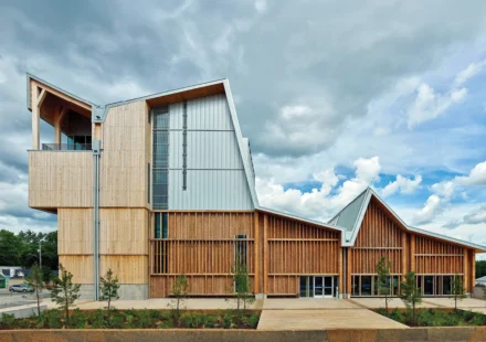 Modern mass timber building with engineered wood facade under dramatic clouds showcasing sustainable architecture design.