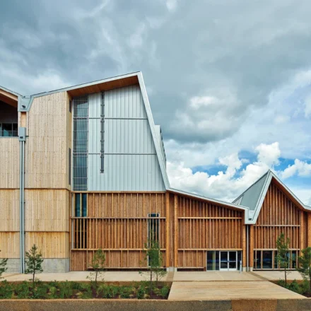 Modern mass timber building with engineered wood facade under dramatic clouds showcasing sustainable architecture design.