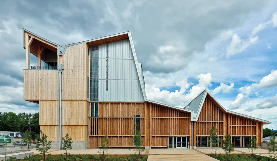 Modern mass timber building with engineered wood facade under dramatic clouds showcasing sustainable architecture design.