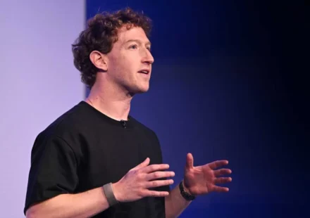 Meta executive speaking onstage in a black shirt, gesturing with both hands against a dark backdrop.