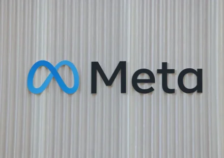 Meta logo displayed on a textured wall, representing WhatsApp scam detection and platform safety updates.