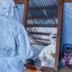 Health workers in protective suits conduct Ebola response work inside a makeshift treatment center.