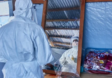 Health workers in protective suits conduct Ebola response work inside a makeshift treatment center.