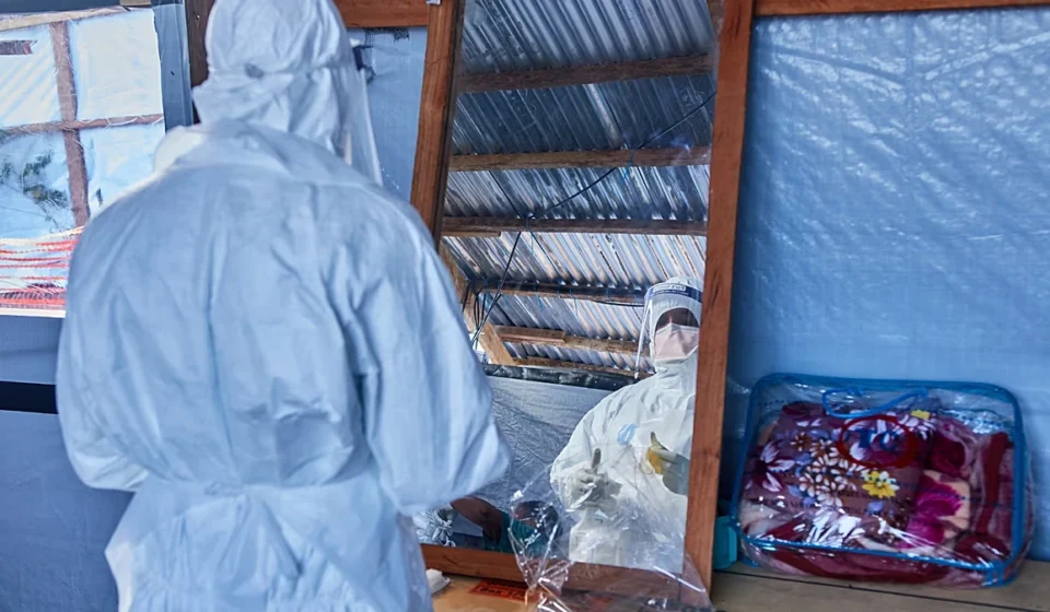 Moderna Advances Experimental Ebola Vaccine to Human Clinical Trials Health workers in protective suits conduct Ebola response work inside a makeshift treatment center.