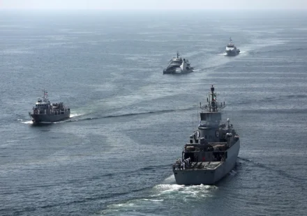Four maritime security vessels patrol open waters during a coordinated high seas security operation.