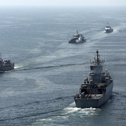 Four maritime security vessels patrol open waters during a coordinated high seas security operation.