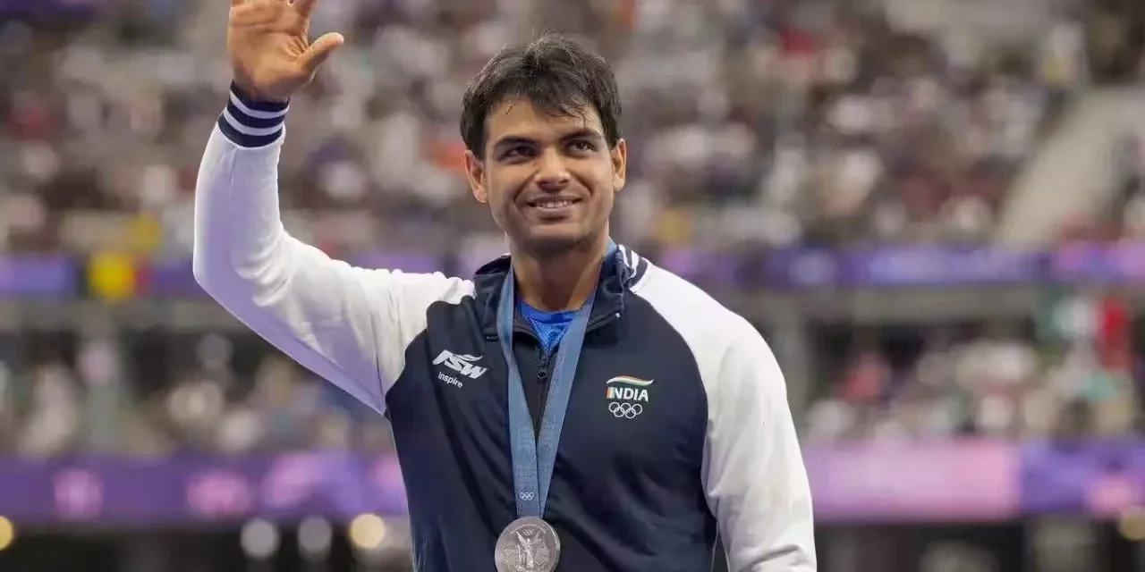 Neeraj Chopra waves while wearing his Olympic silver medal after an international athletics competition.