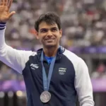 Neeraj Chopra waves while wearing his Olympic silver medal after an international athletics competition.