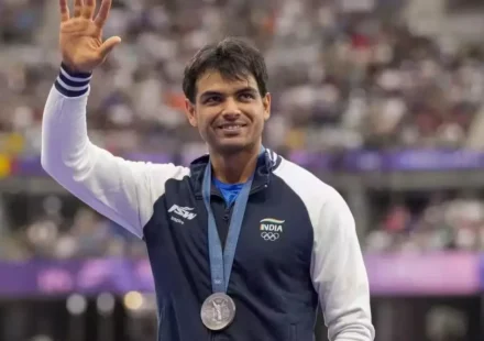 Neeraj Chopra waves while wearing his Olympic silver medal after an international athletics competition.