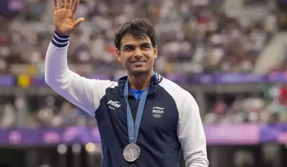Neeraj Chopra waves while wearing his Olympic silver medal after an international athletics competition.