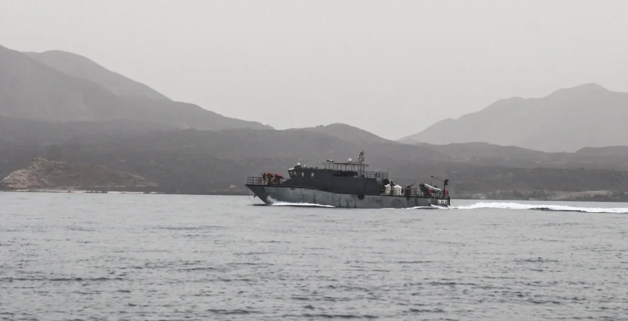 Naval patrol vessel speeds across calm Red Sea waters with rugged mountains in the distant background