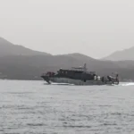 Naval patrol vessel speeds across calm Red Sea waters with rugged mountains in the distant background