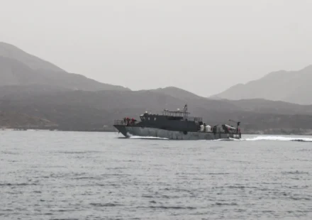 Naval patrol vessel speeds across calm Red Sea waters with rugged mountains in the distant background