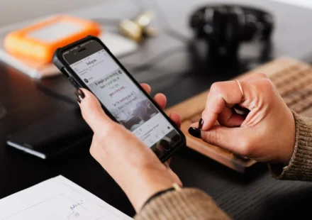 Person browsing social media on a smartphone at a desk during an interactive online campaign today.