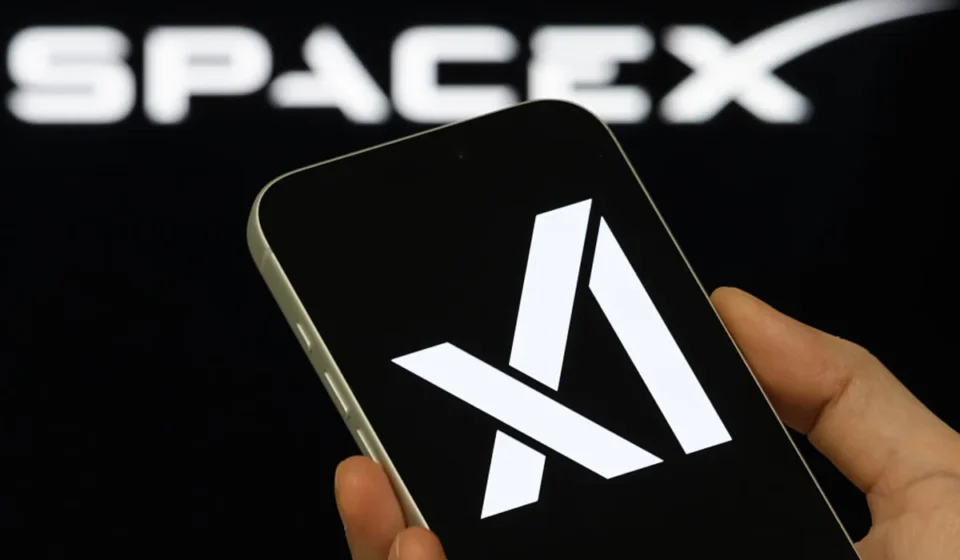 SpaceX and Cloud AI Firms Ink Multi-Billion Dollar Compute Deals Hand holding smartphone showing Anthropic logo with blurred SpaceX branding in background during AI.