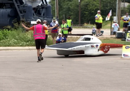 Student built solar car rounds a corner during the Electrek American Solar Challenge event on route.
