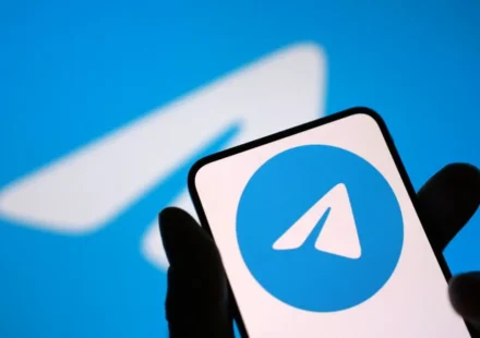 Hand holding smartphone displaying Telegram logo against blue background after App Store return news