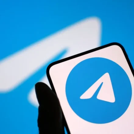 Hand holding smartphone displaying Telegram logo against blue background after App Store return news